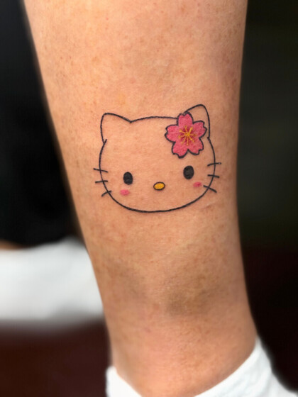 Цветная татуировка Hello Kitty с сакурой на голени