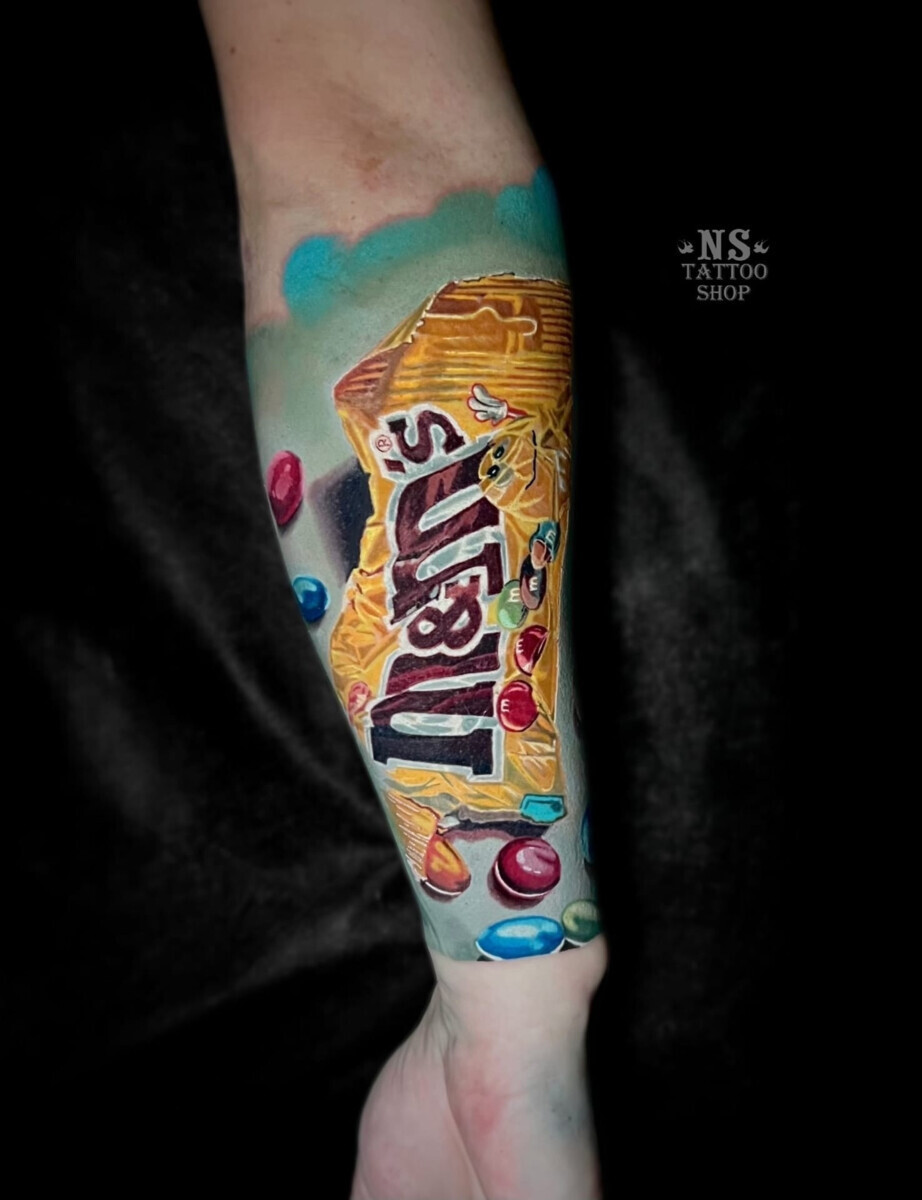 Цветная татуировка M&M's в стиле реализм на предплечье