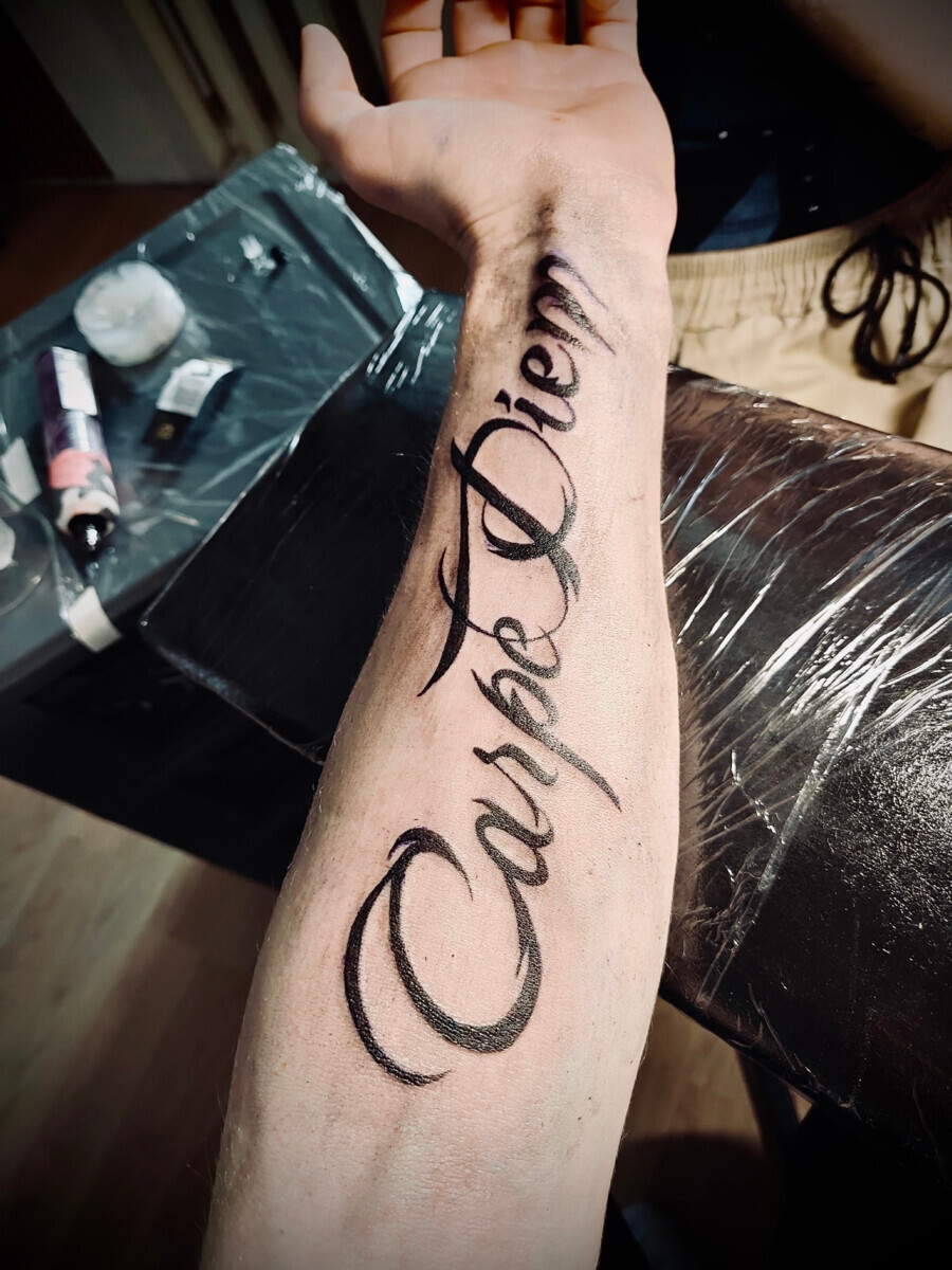 Татуировка надпись Carpe Diem на предплечье в стиле леттеринг