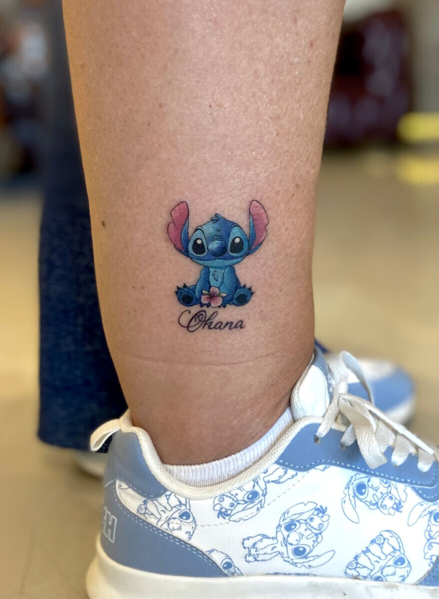 Цветная татуировка Стич с надписью Ohana на ноге