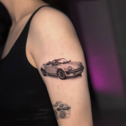 Татуировка с автомобилем Porsche в стиле реализм на плече