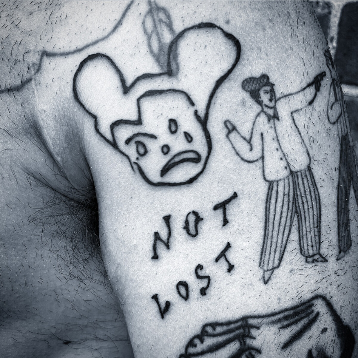 Черно-белая татуировка в стиле ар-брют: грустный персонаж и надпись Not Lost