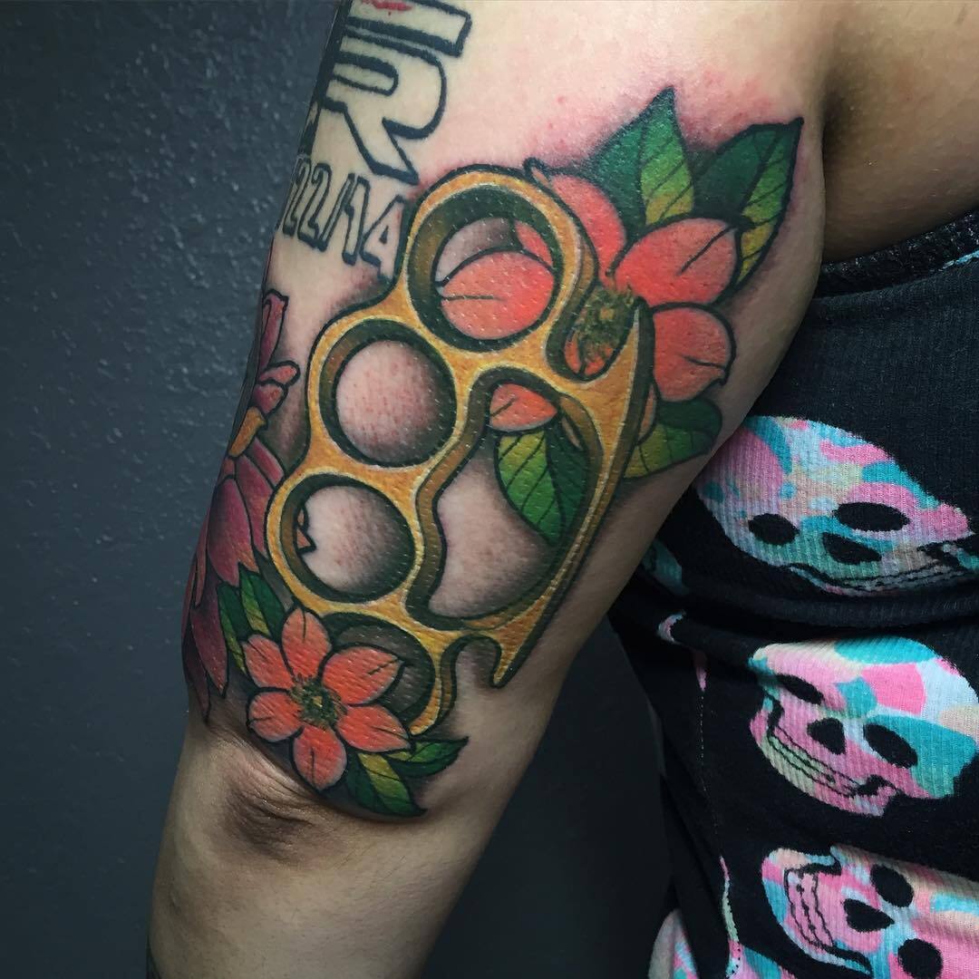 Изображение кастета с цветами на бицепсе парня