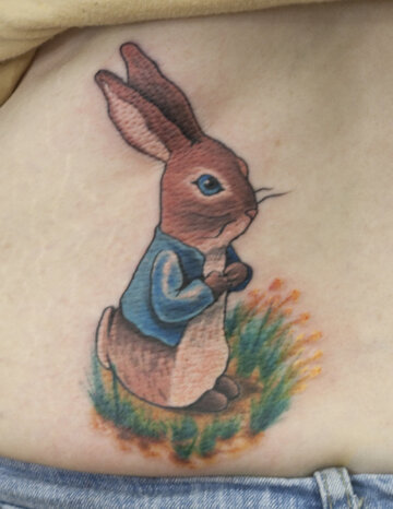 Тату на пояснице девушки - заяц на травке