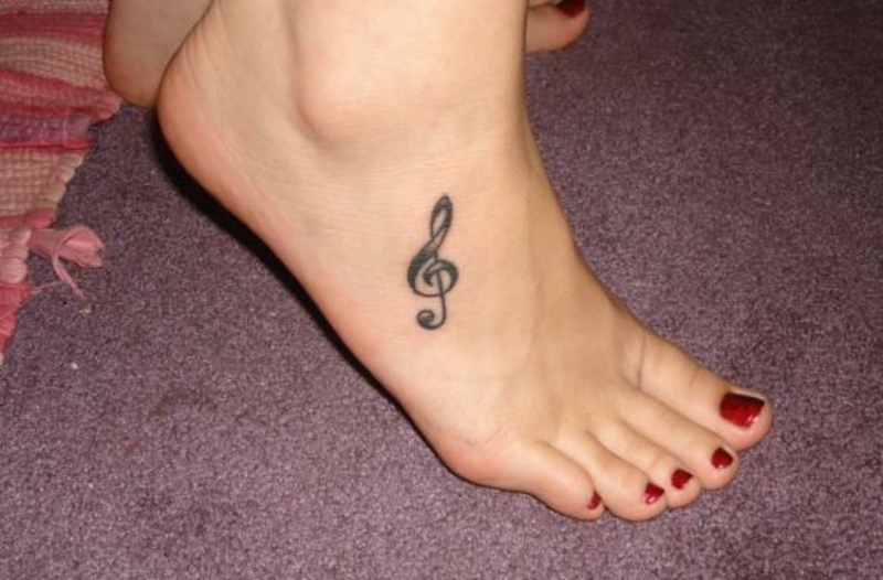 Татуха на ступне девушки - скрипичный ключ